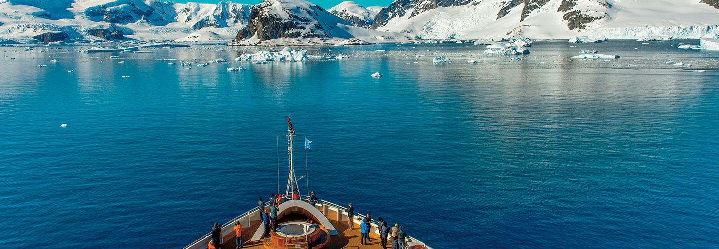 view from front of a ship as it sails toward snow-covered land