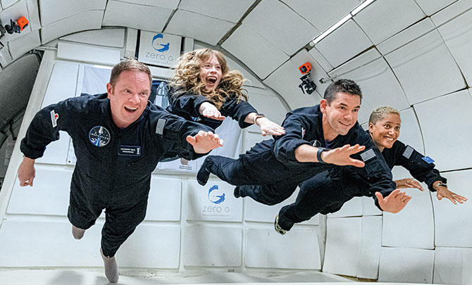 Enlargeable photo of four people including Hayley floating in their space craft