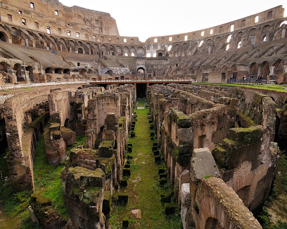 The colosseum overgrown by grass and weeds and abandoned except for tourists