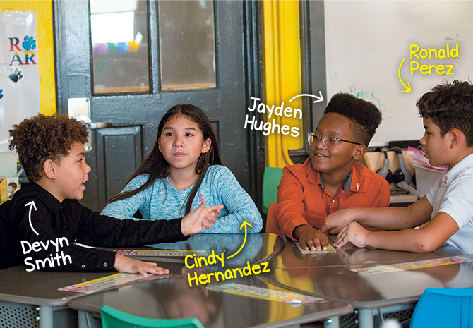 Enlargeable photo of students sitting a their desks and having a conversation