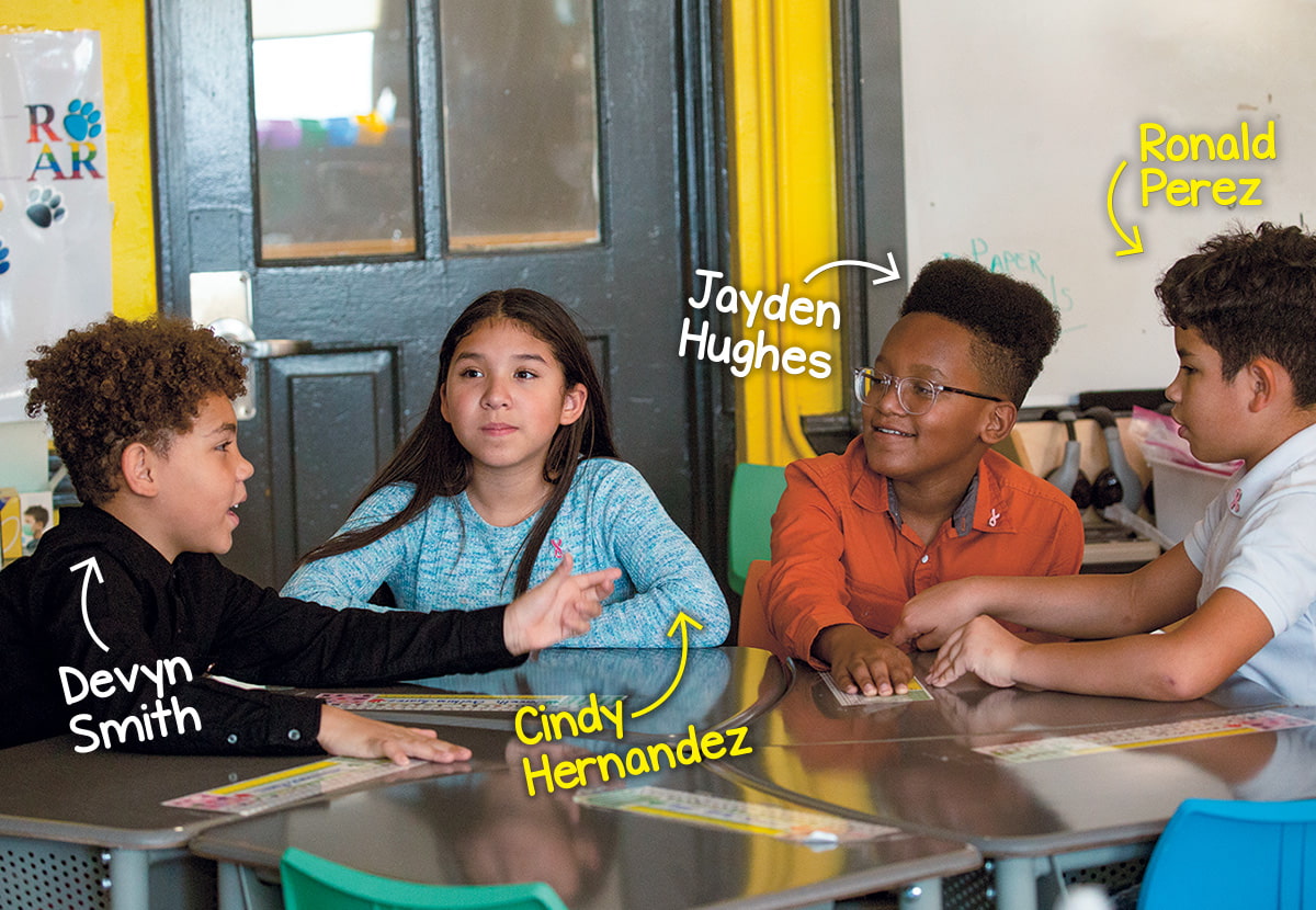 Photo of students sitting a their desks and having a conversation