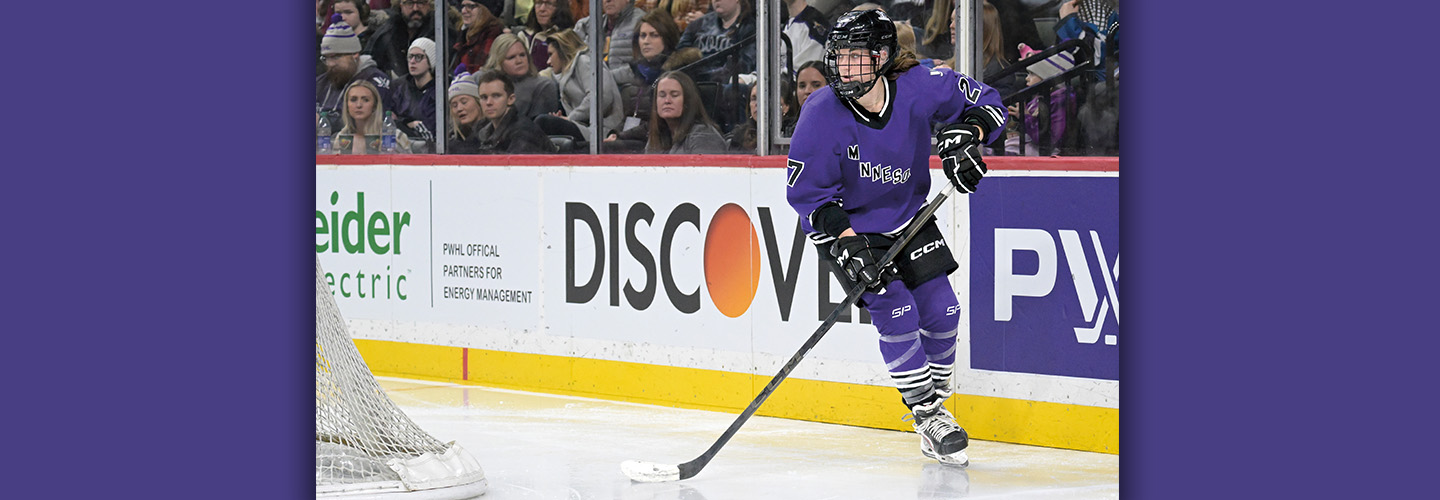 Photo of a hockey player on ice while a crowd watches from behind glass