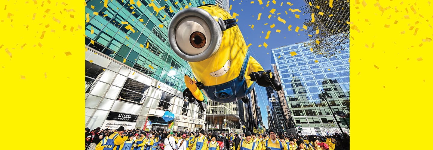a large Minion balloon soars above a crowd
