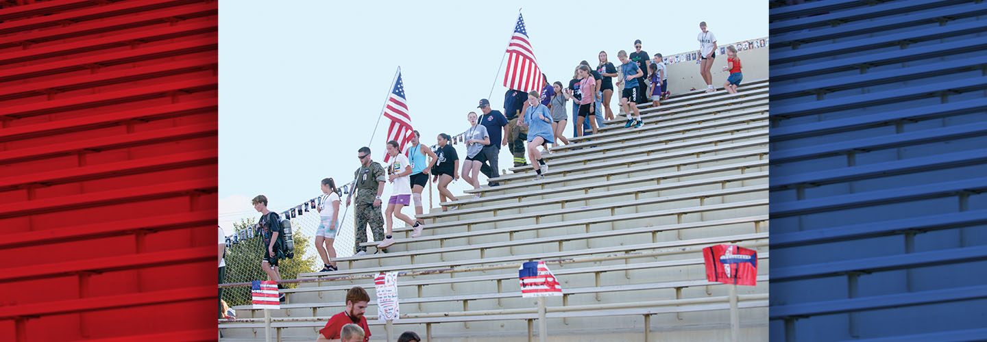 hoto of firefighters, police officers, and people walking on bleachers